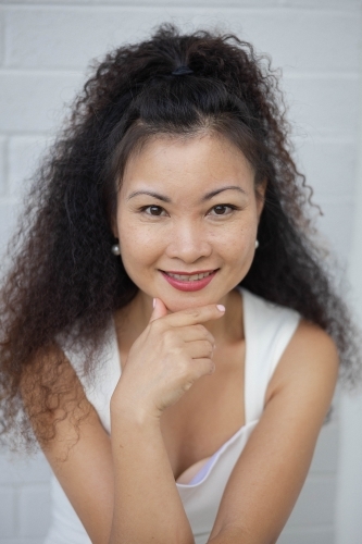 Portrait of woman smiling against blank wall - Australian Stock Image