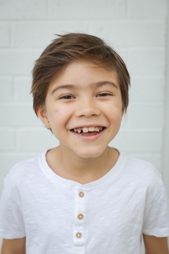 Portrait of young boy against white wall - Australian Stock Image
