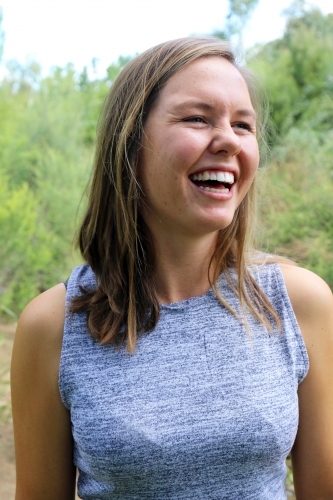 Portrait of young female laughing outdoors with trees in background - Australian Stock Image