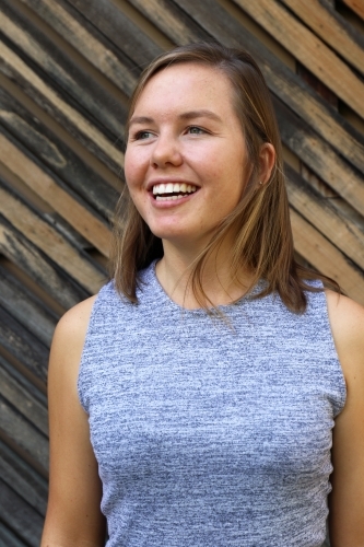 Portrait of young female outdoors with textured wooden background - Australian Stock Image