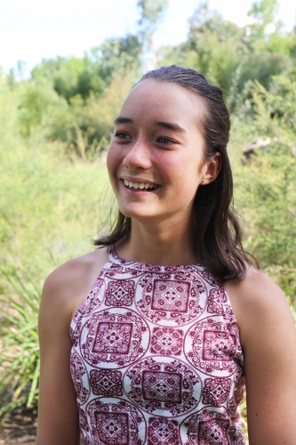 Portrait of young female outdoors with trees in background - Australian Stock Image