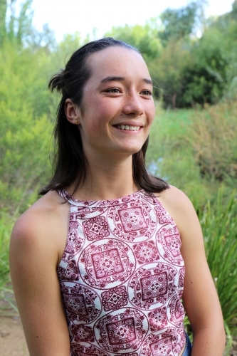 Portrait of young female outdoors with trees in background - Australian Stock Image