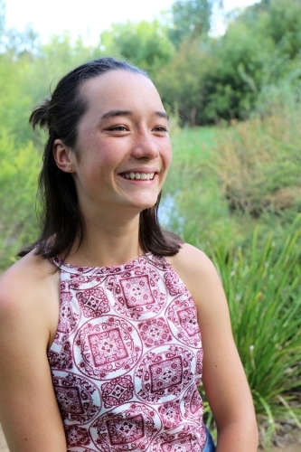 Portrait of young female outdoors with trees in background - Australian Stock Image