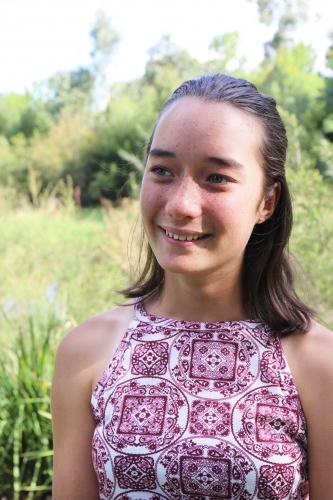 Portrait of young female outdoors with trees in background - Australian Stock Image