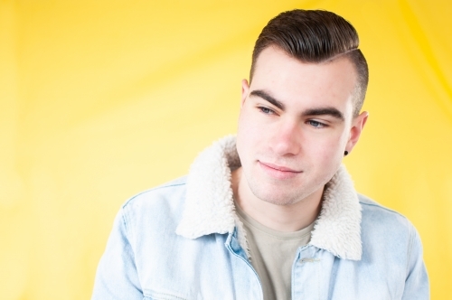 Portrait of young man looking down on plain yellow background