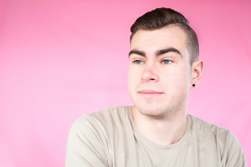 Portrait of young man on plain pink background