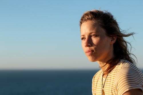 Portrait of young woman in morning sunlight by the ocean - Australian Stock Image