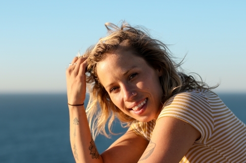 Portrait of young woman in morning sunlight by the ocean - Australian Stock Image