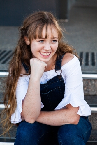 Portrait of young woman in overalls looking down - Australian Stock Image