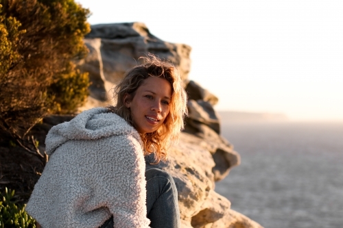 Portrait of young woman on coastal clifftop at sunrise