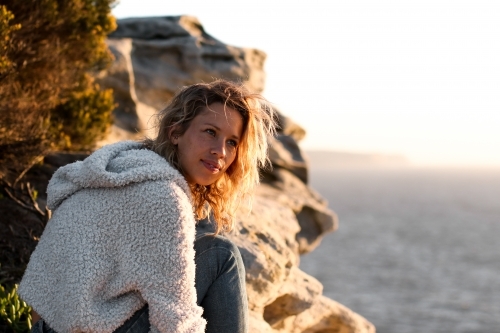 Portrait of young woman on coastal clifftop at sunrise