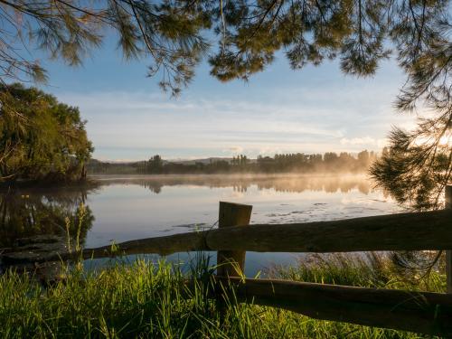 Post and rail fence overlooking a dam with mist rising - Australian Stock Image