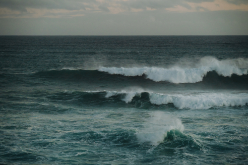 Powerful ocean waves crashing beneath grey cloudy sky - Australian Stock Image