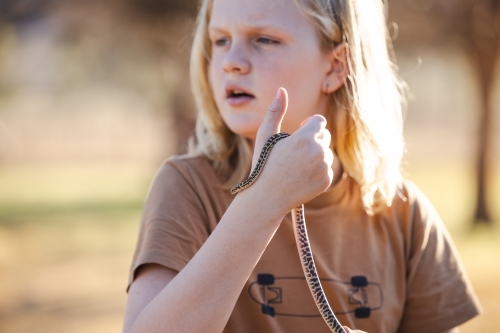 Pre-teen adolescent boy holding pet children's python snake - Australian Stock Image