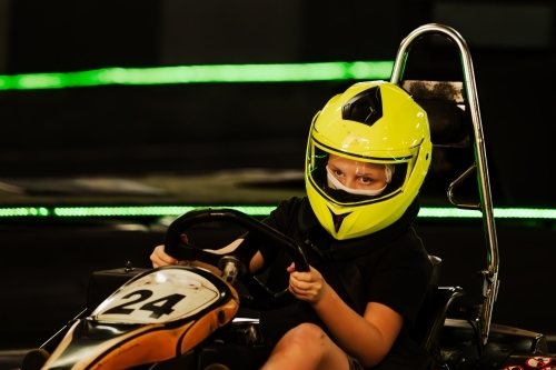 Pre-teen boy driving Go Kart on indoor race track circuit - Australian Stock Image