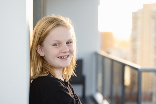 Pre-teen boy leaning against wall on balcony of high rise building on the Gold Coast - Australian Stock Image