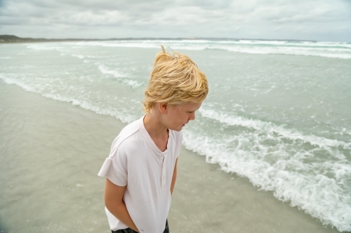 Pre-teen boy on the beach on overcast day - Australian Stock Image
