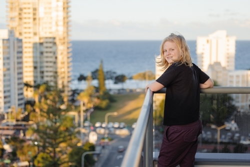 Pre-teen boy standing on balcony of high rise building on the Gold Coast with view - Australian Stock Image