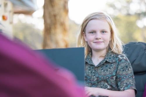 Pre-teen boy studying on laptop outdoors. Homeschool education while travelling Australia - Australian Stock Image