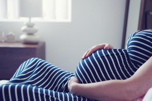 Pregnant Mother relaxing on bed - Australian Stock Image