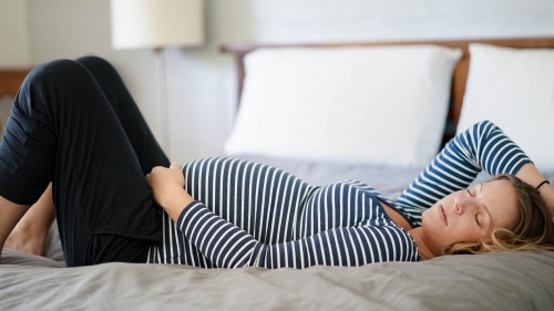 Pregnant woman laying sideways on bed sleeping