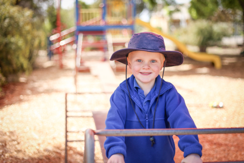 Preschool boy posing on climbing frame for kindergarten photos. Outdoor portrait. - Australian Stock Image