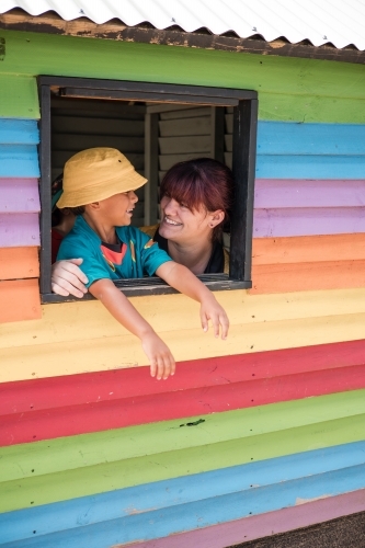 Preschool educator with young Aboriginal  boy in cubby house window - Australian Stock Image