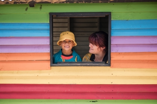 Preschool teacher with young Aboriginal  boy in cubby house window - Australian Stock Image