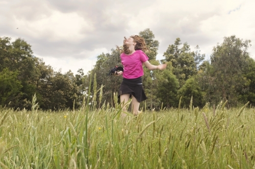 Preteen girl running happily through green paddock