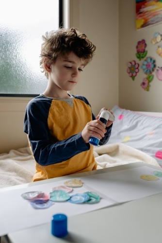 Primary school boy at home remote learning, working on maths lesson pasting numbers in order - Australian Stock Image