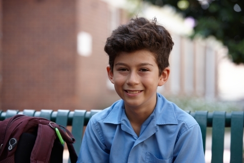 Primary school student at sitting with backpack smiling - Australian Stock Image