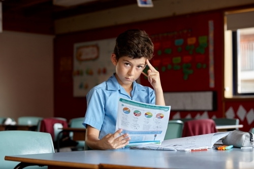 Primary school student in classroom working on homework - Australian Stock Image