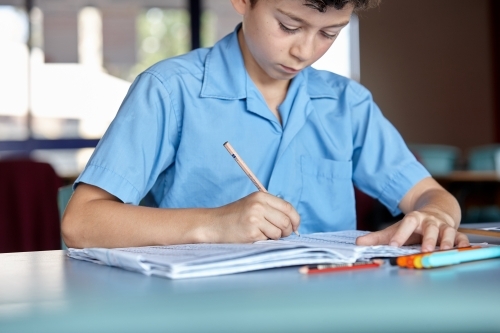 Primary school student in classroom working on homework - Australian Stock Image