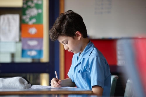 Primary school student in classroom working on homework - Australian Stock Image
