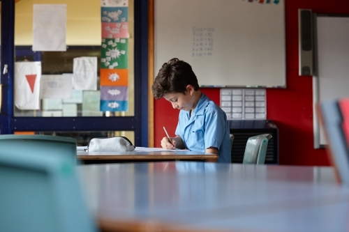 Primary school student in classroom working on homework - Australian Stock Image