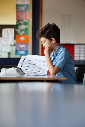 Primary school student in classroom working on homework - Australian Stock Image