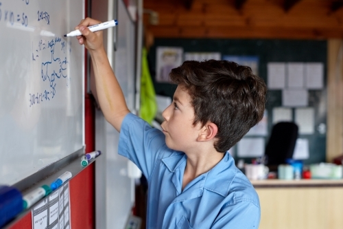 Primary school student writing on whiteboard - Australian Stock Image