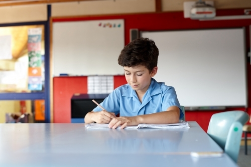Primary school student in classroom working on homework - Australian Stock Image