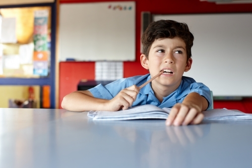 Primary school student in classroom working on homework - Australian Stock Image