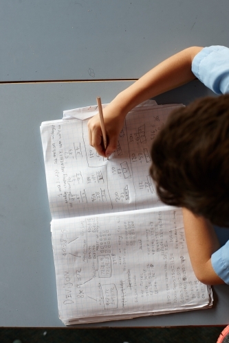 Primary school student in classroom working on homework - Australian Stock Image