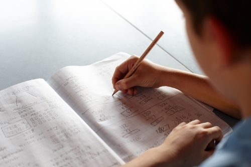 Primary school student in classroom working on homework - Australian Stock Image