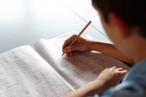Primary school student in classroom working on homework - Australian Stock Image