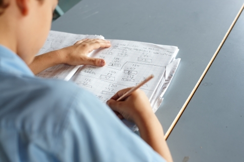 Primary school student in classroom working on homework - Australian Stock Image