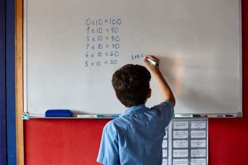 Primary school student writing on whiteboard - Australian Stock Image