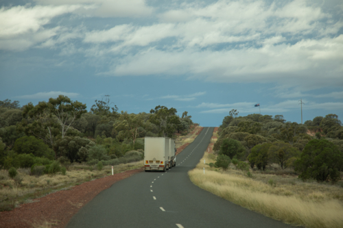 Prime mover pulling two curtain sided trailers going up a jump-up - Australian Stock Image
