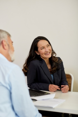 Professional business man and woman sitting chatting in a studio - Australian Stock Image