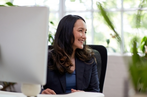 Professional business woman sitting at a desk with a computer - Australian Stock Image