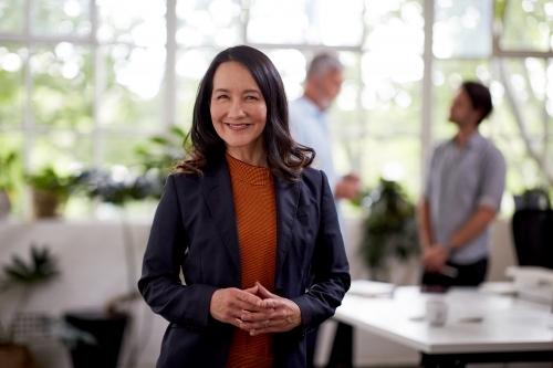 Professional business woman standing thinking in a studio office - Australian Stock Image