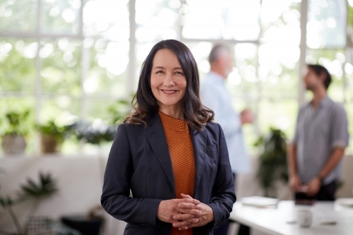 Professional business woman standing, thinking in an open studio - Australian Stock Image