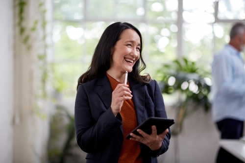 Professional business woman standing, thinking in an open studio - Australian Stock Image